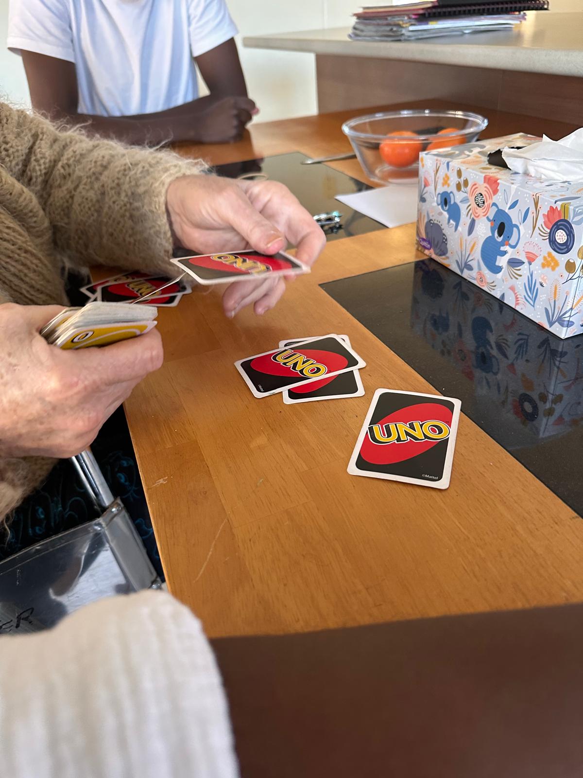 Participant and support worker playing a game of UNO together